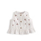 White sleeveless swing top with cherry print, gold buttons, and ruffled hem