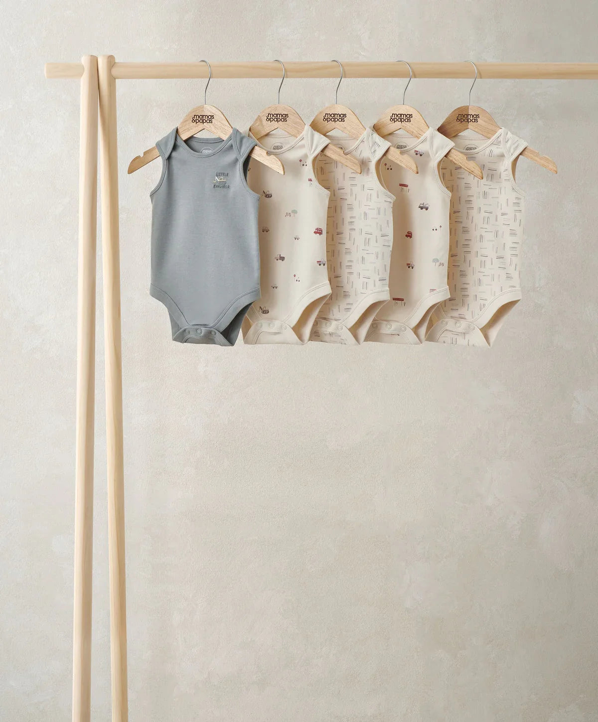 Pack of five short-sleeved baby bodysuits on hangers, gray and cream tones
