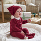 Red knitted baby hat on baby with ribbed cuff and white pom-pom