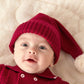 Red knit baby hat close-up with ribbed edge and white pom-pom