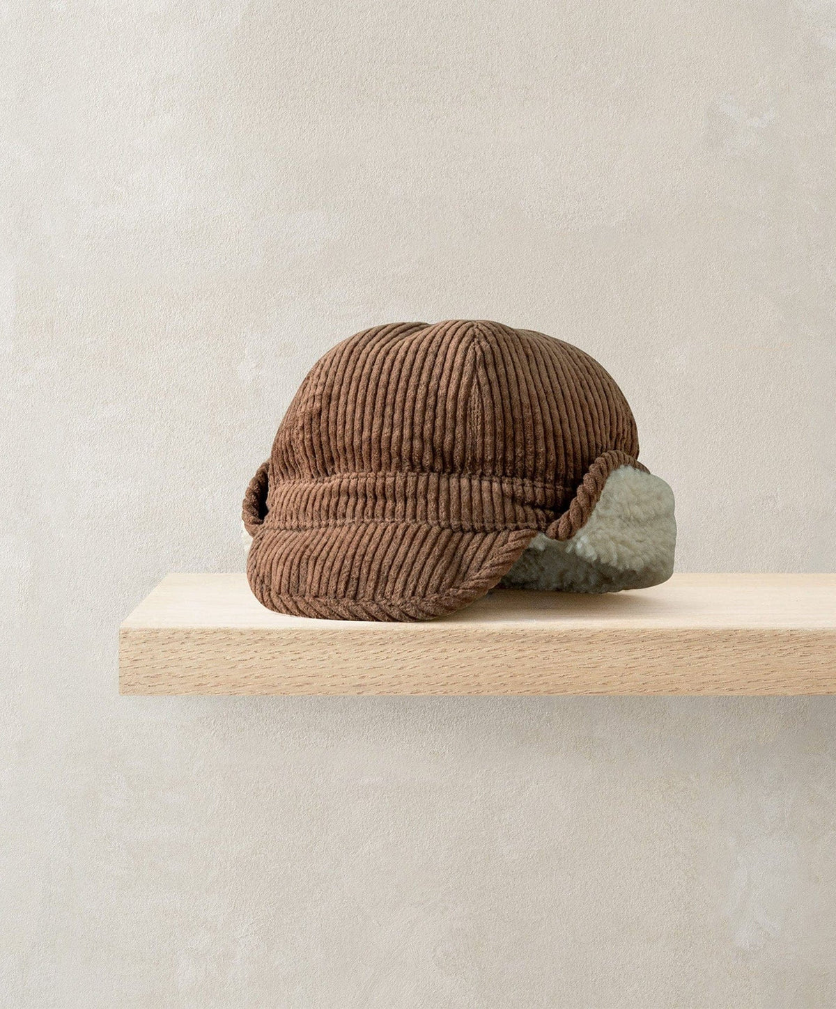 Brown trapper hat with ribbed knit texture and gray faux-fur earflaps