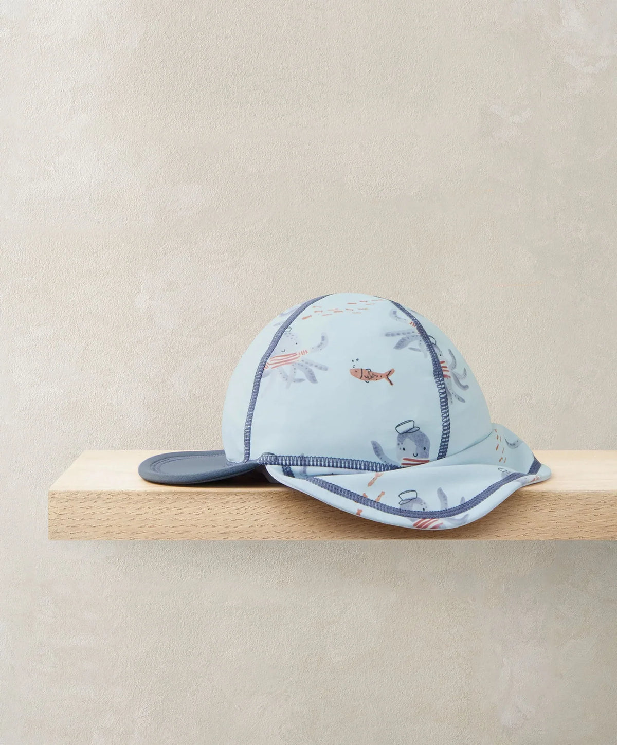 Squid print swim cap, light blue with navy brim and side flap, orange and gray squid