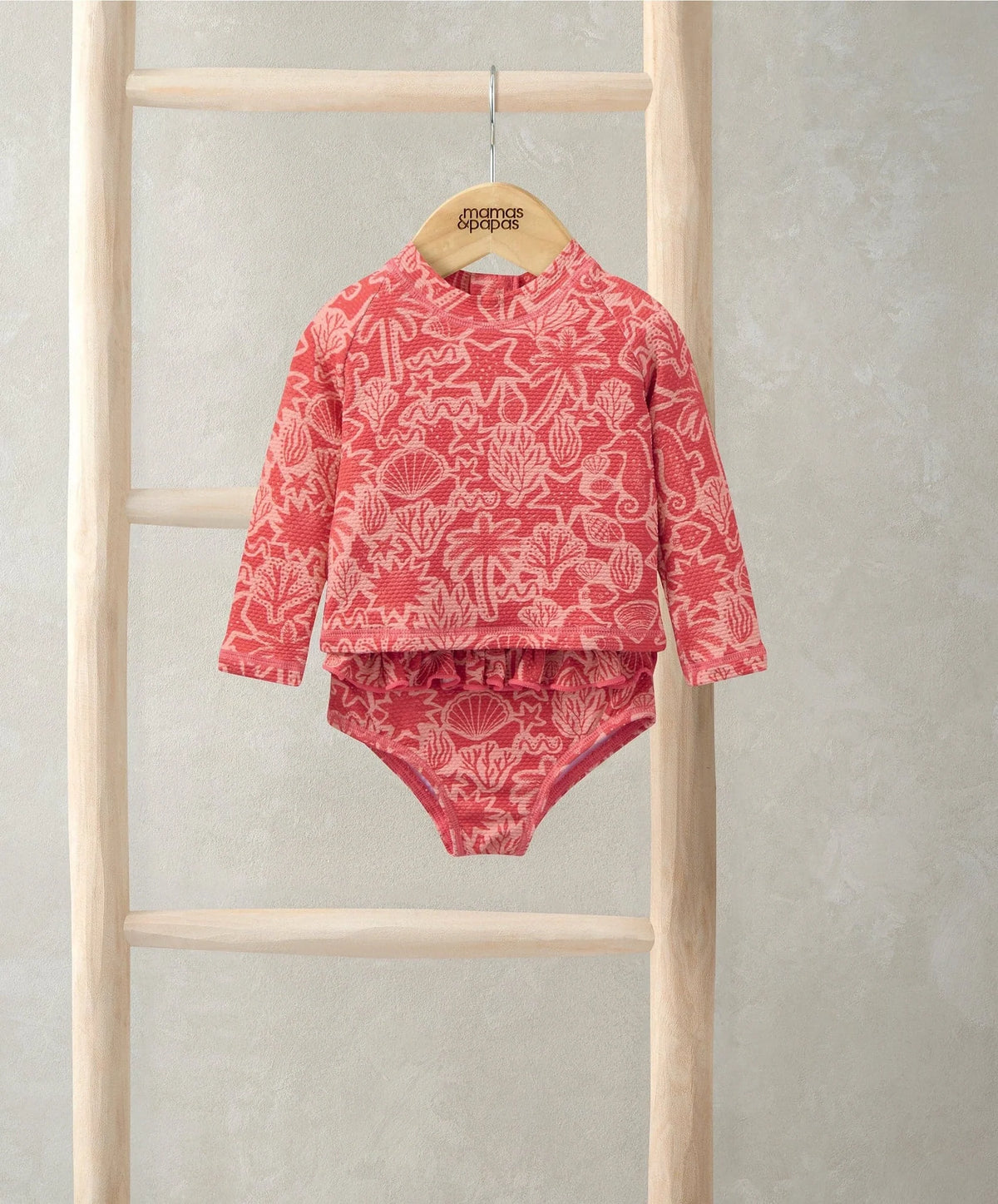 Coral pink long-sleeve rash guard swimsuit with sea-life print and ruffled waist