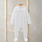 White embroidered baby romper on hanger, long sleeves, collar and chest text
