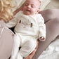 Velour all-in-one baby suit in white with long sleeves and Christmas graphic, worn by baby