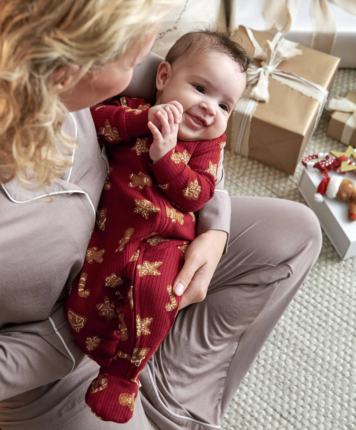 Baby all-in-one romper in dark red with gingerbread cookie print, long sleeves, footed