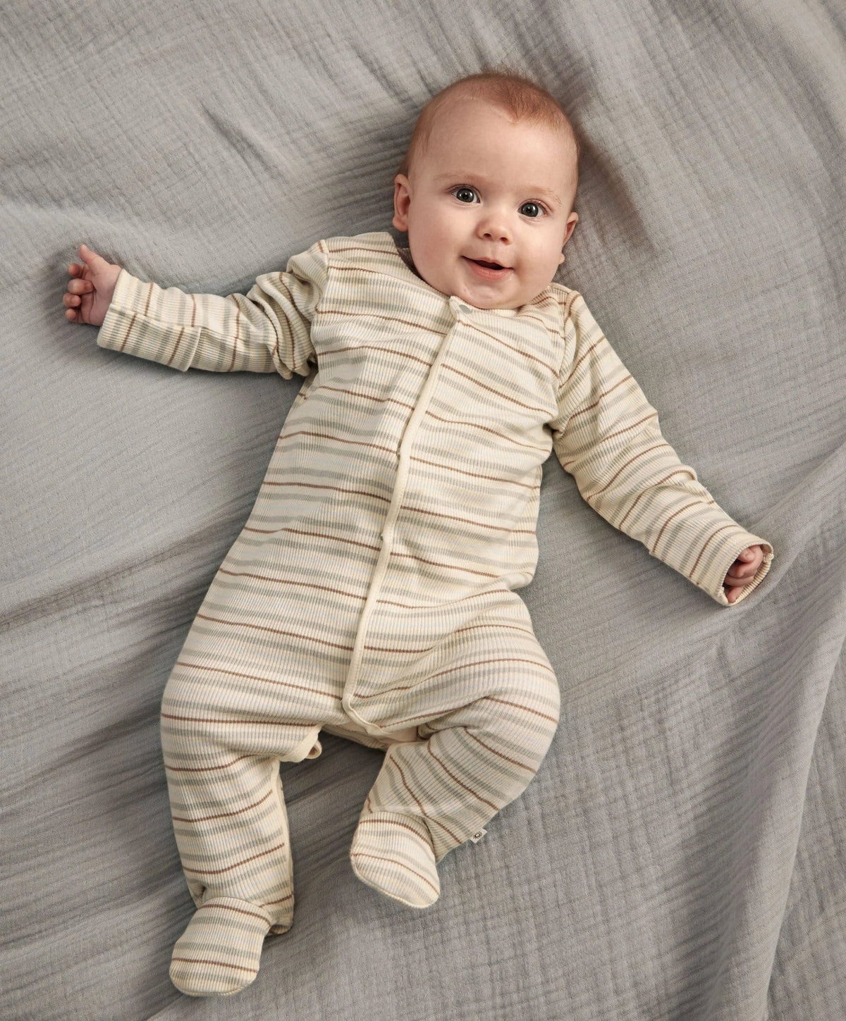 Ribbed stripe sleepsuit on baby: cream with horizontal gray-blue stripes, footed legs.
