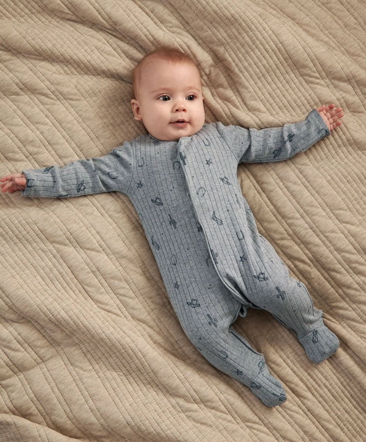Blue knit footed sleepsuit with zipper and allover Western-style icons.