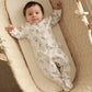 Daisy-print footed sleepsuit with long sleeves, white fabric and pastel floral pattern