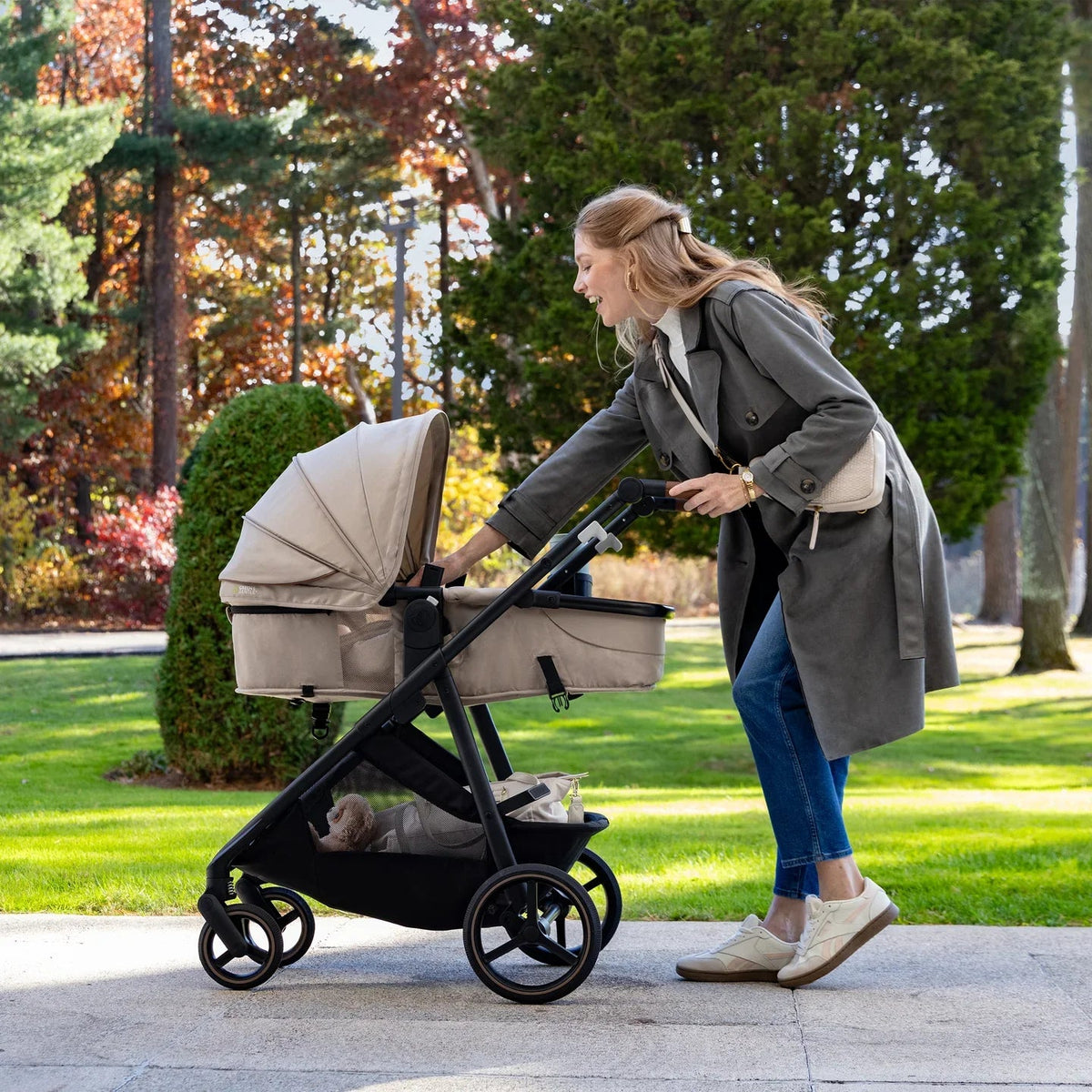 Light beige stroller with open seat and canopy on black frame.