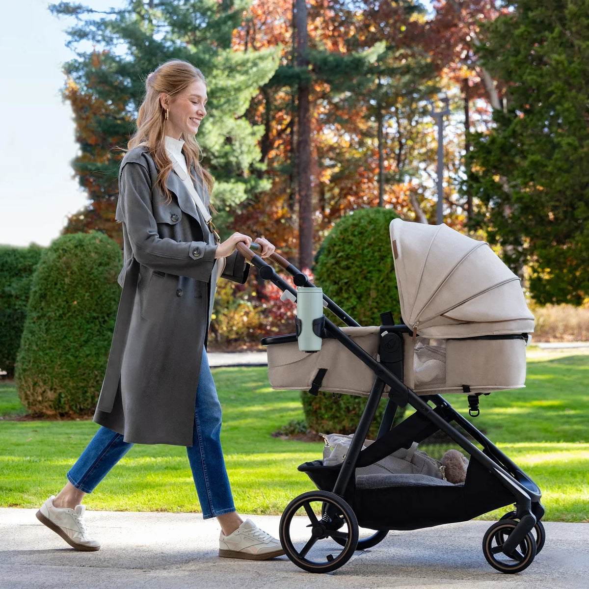 Light beige stroller with canopy and black frame outdoors.