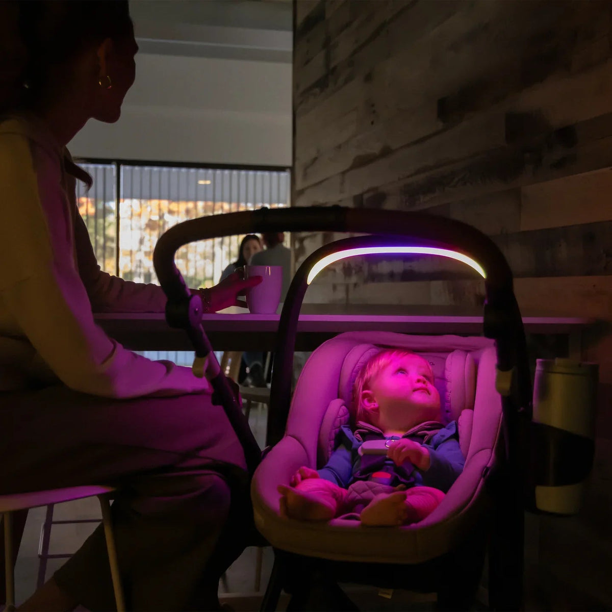 Beige baby stroller with canopy and child in seat, purple-lit head area