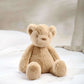 Beige teddy bear soft toy sitting on its own, side view with rounded ears