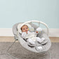 Pebble grey baby bouncer cradle with curved frame, toy arch, and seated baby