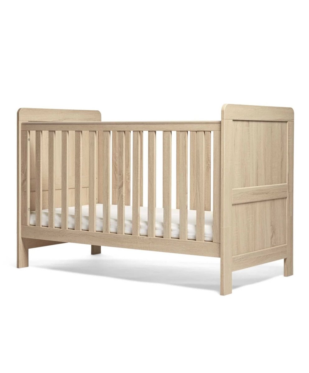 Light oak cotbed with paneled ends and vertical slat mattress rails