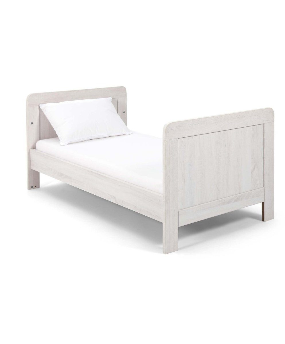 Light gray cotbed with vertical slat rails, cushioned end panel details, studio view