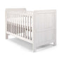 White wood cotbed with vertical slats and two end panels, front three-quarter view
