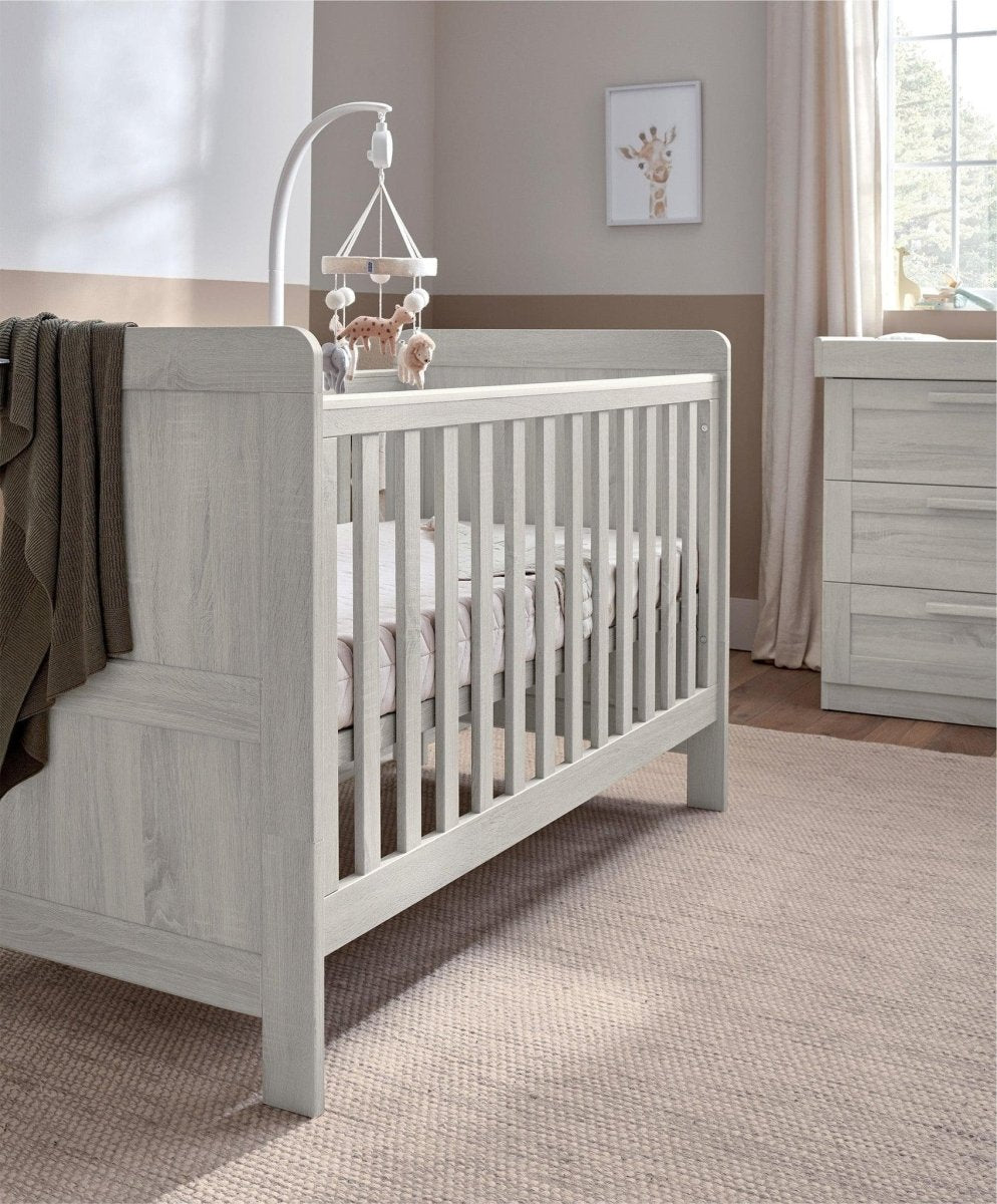 Light gray wood cotbed with vertical rails and two end panels, side view