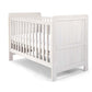White wood cotbed with vertical slats and two padded end panels, angled view