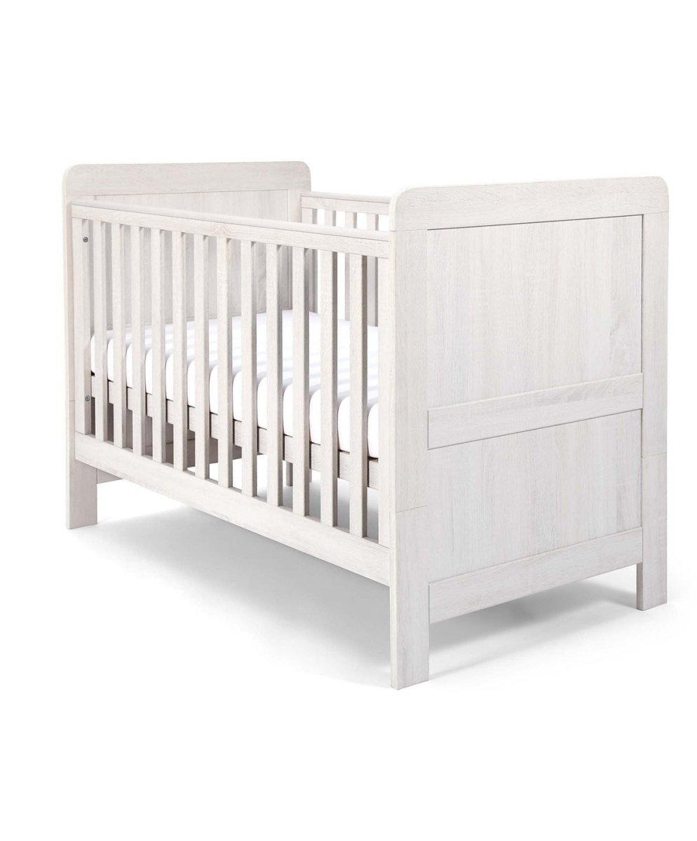 White wood cotbed with vertical slats and two padded end panels, angled view