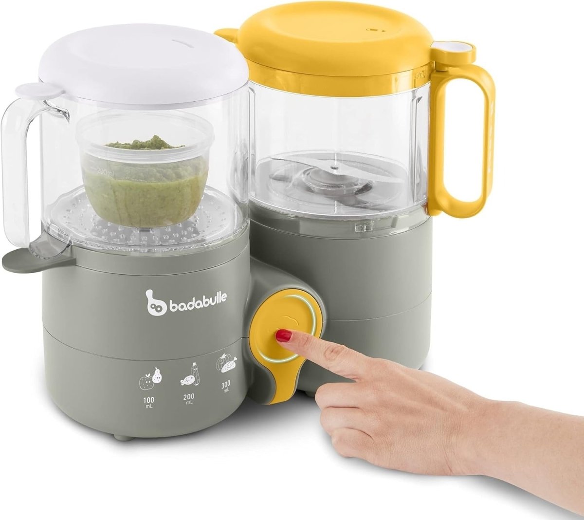 Baby food processor with two clear jars, yellow lid, and finger on the control dial