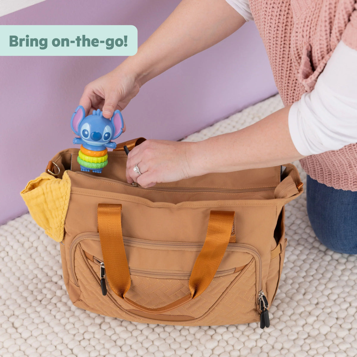 Blue baby fidget toy with stacked rainbow rings inside a tote bag pocket