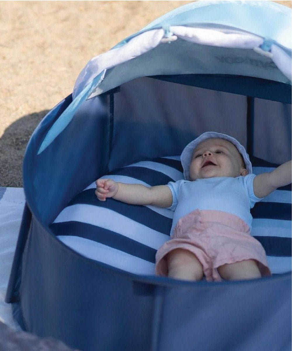 Baby lying inside navy pop-up play tent with striped liner and open mesh roof