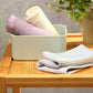 Bamboo washcloths folded in a bowl, striped towels in white, gray, and mauve