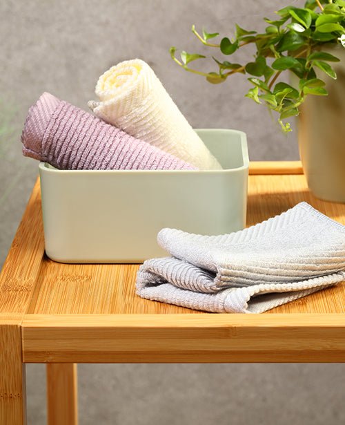Bamboo washcloths folded in a bowl, striped towels in white, gray, and mauve