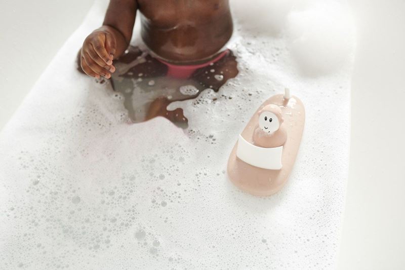 Pink monkey bath toy in water with white seat on curved bath boat