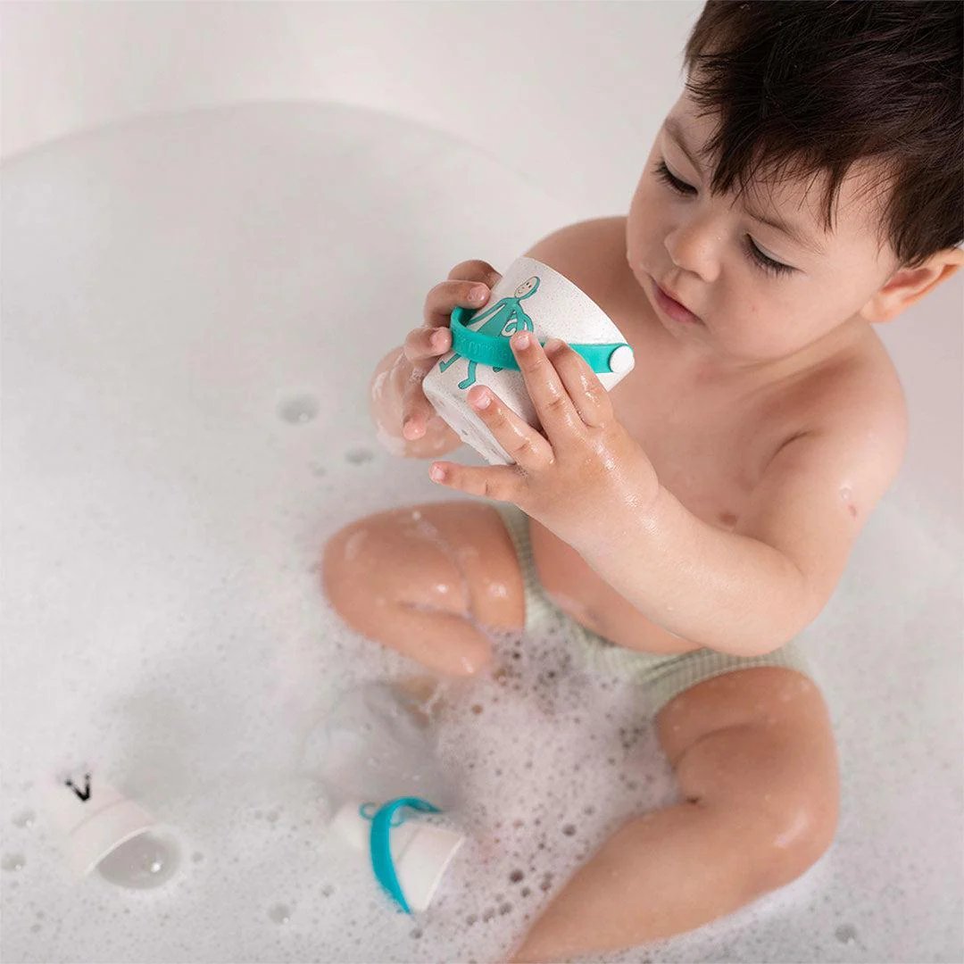 Kid rinsing with a small green bath bucket, pouring water in a bathtub