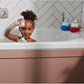 Bath toy wobblers on bathroom tub ledge, with green and red character faces