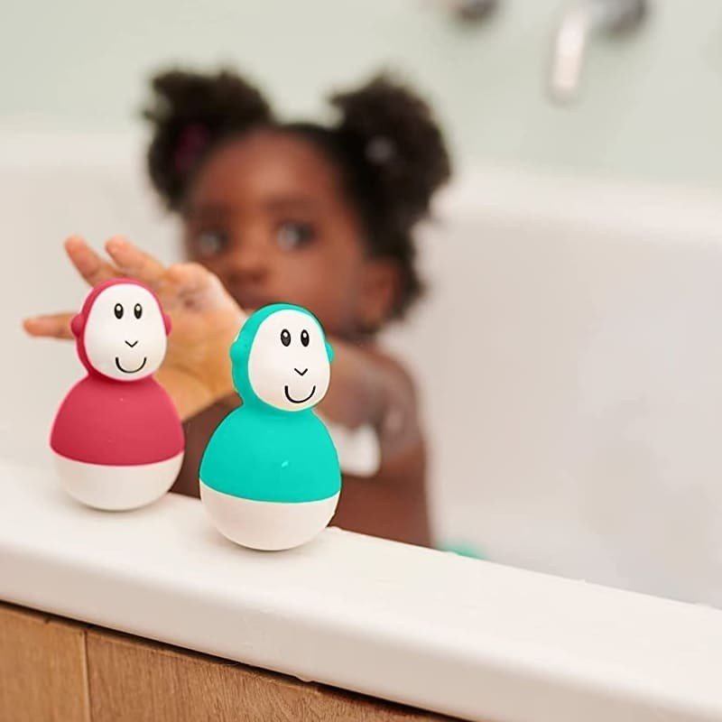 Bath toy wobblers, green and red animal-face figures beside a child's bath