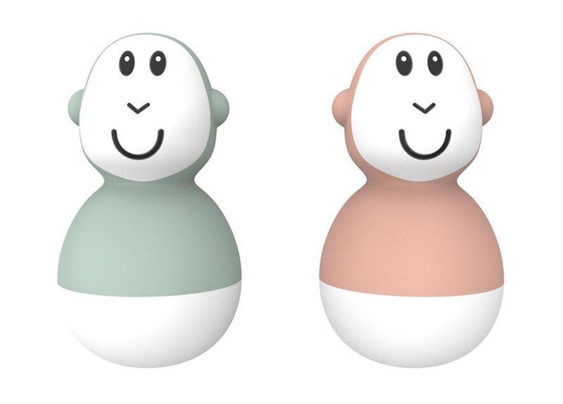 Two bath wobbler toys with smiling faces in mint and peach, rounded with small side nubs.