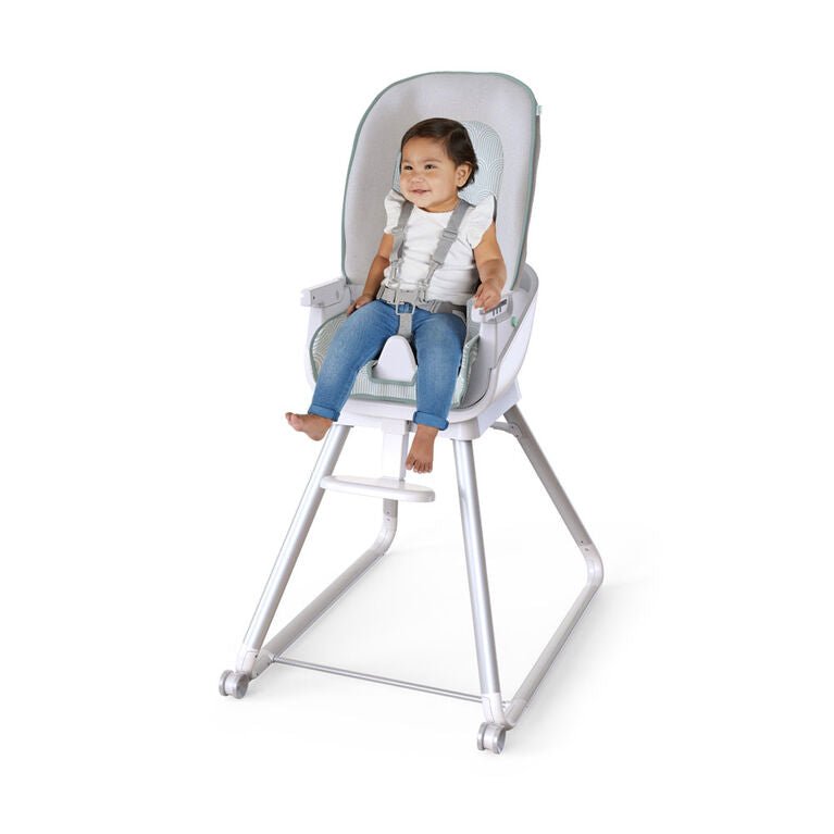 Gray high chair with clear tray and padded seat, child seated on footrest