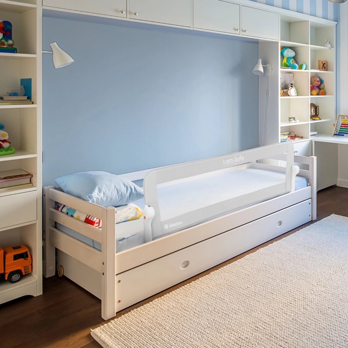 White-framed safety bed rail with gray fabric panel on a twin bed