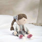 Seated rag doll with braided brown hair, blue bow, gray jacket and floral skirt, pink shoes