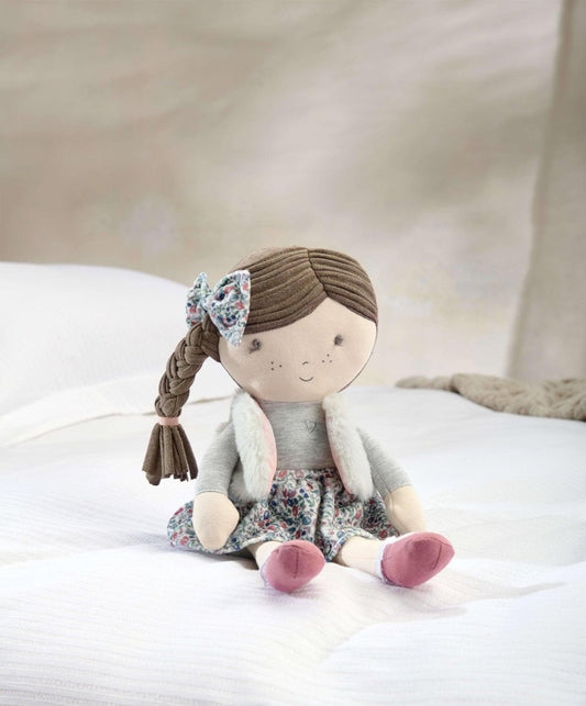 Seated rag doll with braided brown hair, blue bow, gray jacket and floral skirt, pink shoes