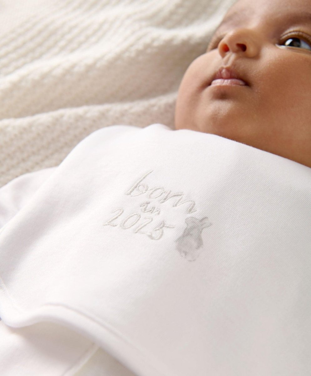 White baby bib front close-up with embroidered “Born 2025” text and motif