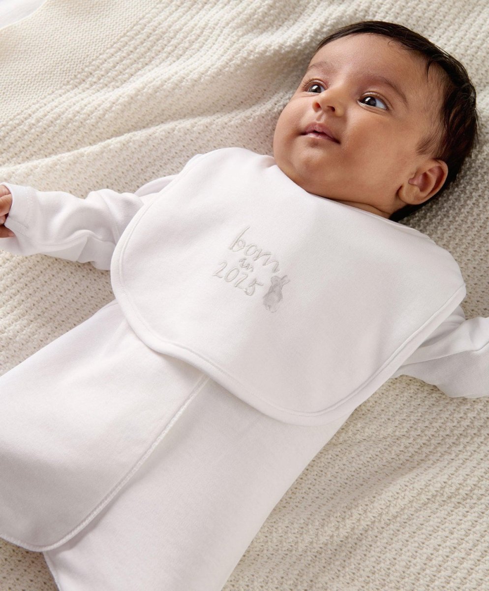 White baby bib worn by baby, with “Born 2025” embroidery on the front