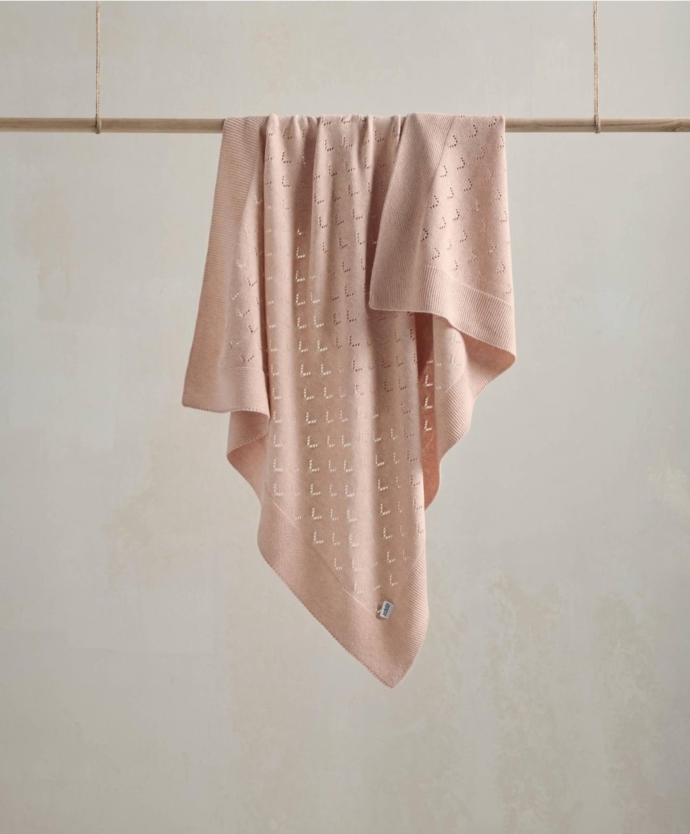 Pink pointelle baby blanket with allover scattered pattern, draped