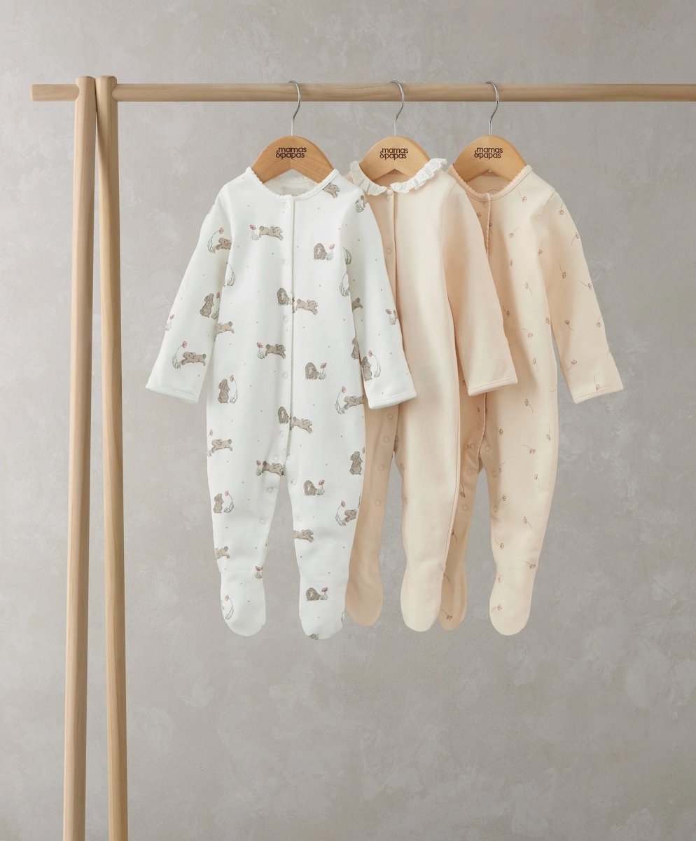 Footed baby sleepsuit set of three with bunny prints in pastel colors on hangers
