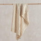 Cream cable-knit baby blanket with cable pattern and fringed edges
