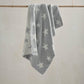 Chenille blanket in light grey with white star pattern, draped view