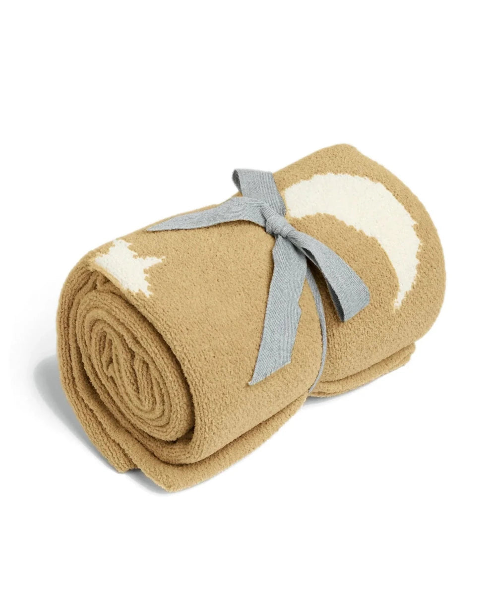 Rolled mustard chenille blanket with white moons and stars, tied with gray ribbon