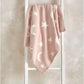 Pink chenille blanket with white stars and crescent moons, draped front