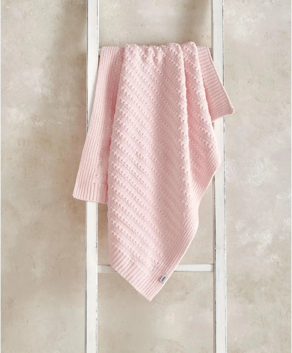 Pink striped chenille blanket with textured knit pattern, draped over a stand