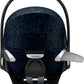 Infant car seat with dark blue patterned headrest cover and black safety straps