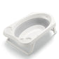 Collapsible baby bath with grey inner tub and perforated support, white frame