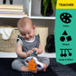 Baby holding a white sensory popper toy with orange cube, striped outfit visible